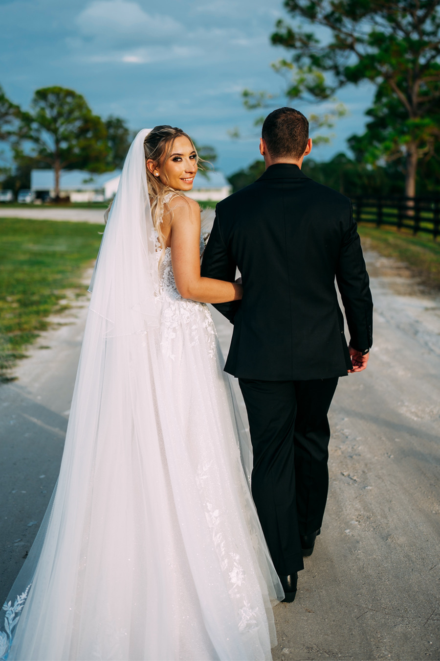 Bride looking back while walking with groom at Ever After Farms Ranch